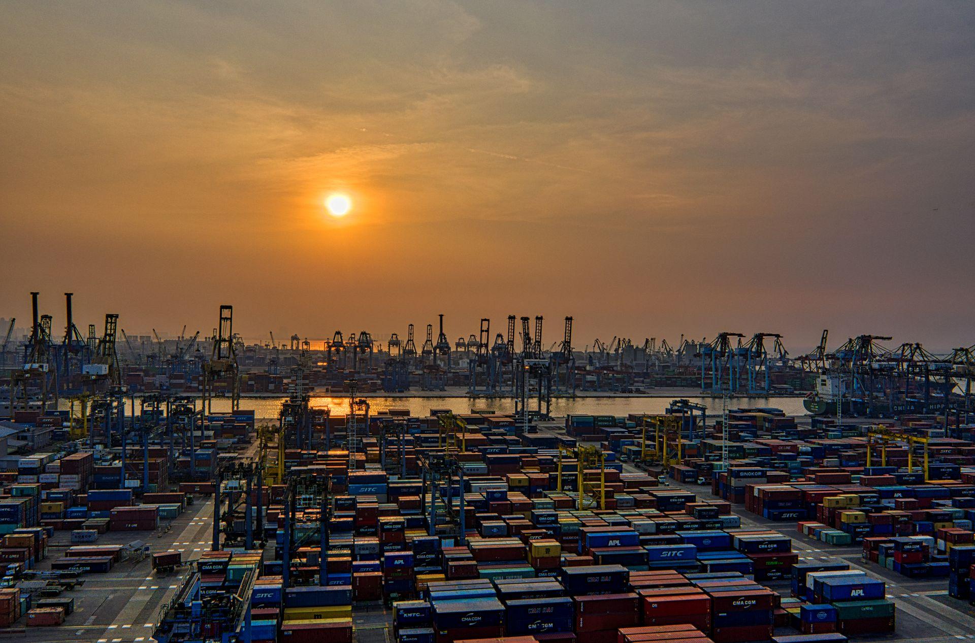 Shipping port at sunset with cargo containers and cranes