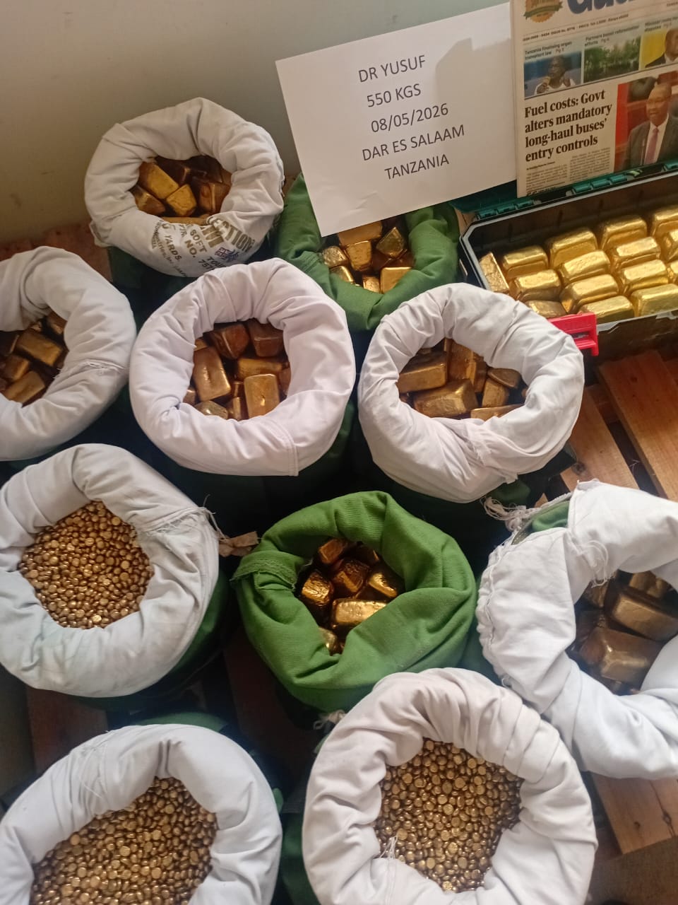 Raw gold nuggets and refined bars displayed on a dark surface under warm lighting