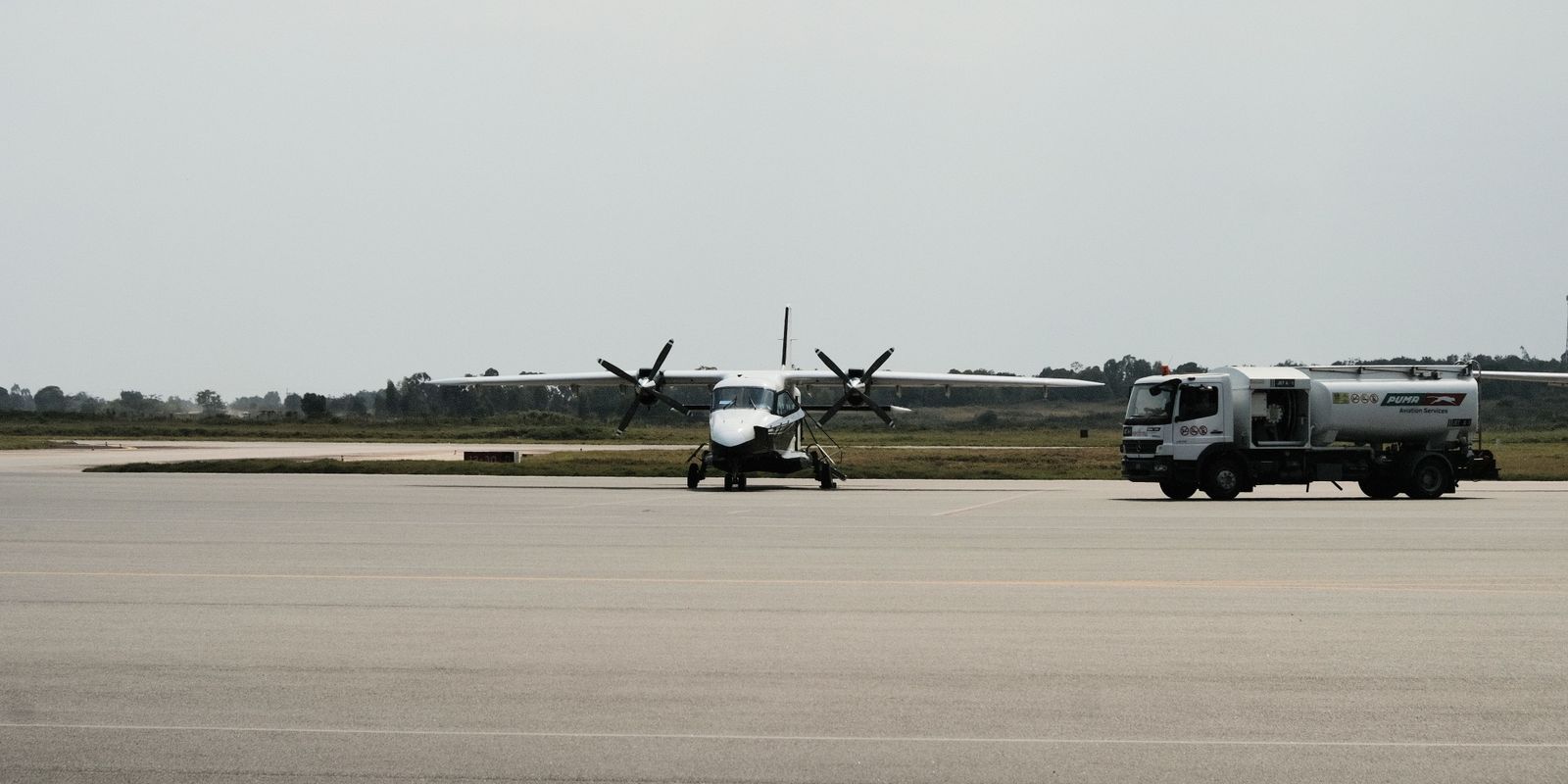 Aircraft refueling on an airport tarmac at golden hour, fuel truck alongside the plane
