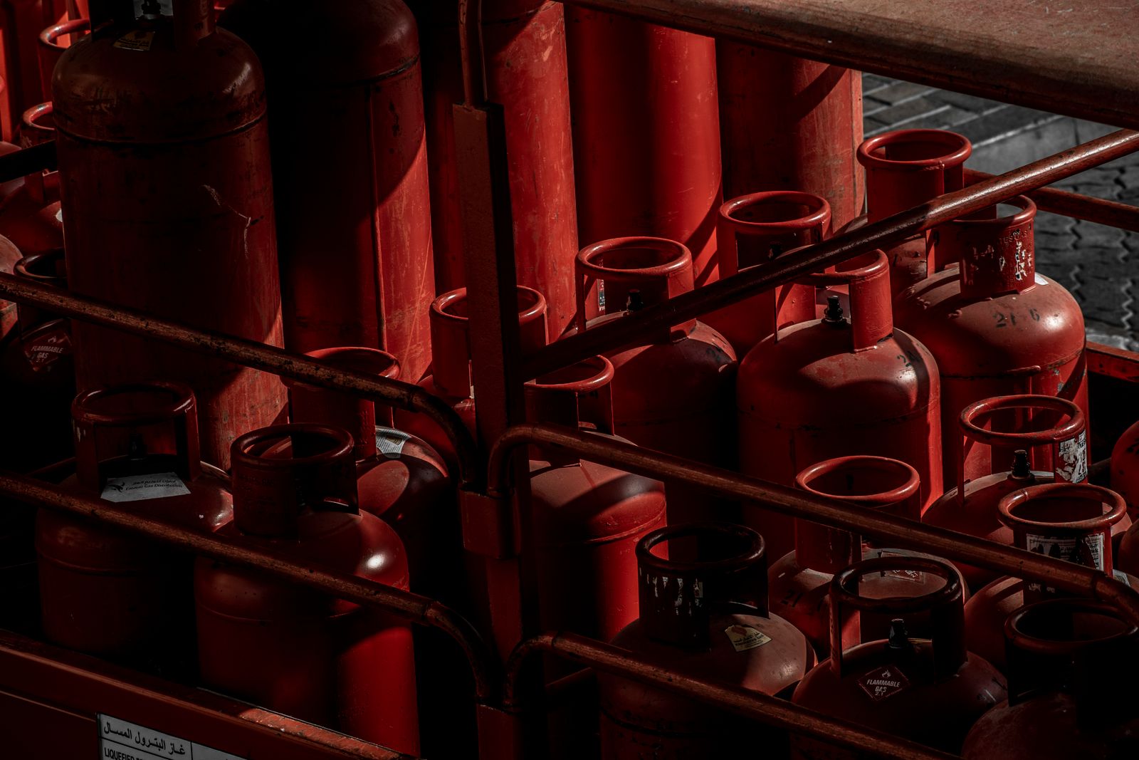 Stacked LPG gas cylinders in a warehouse under warm directional lighting